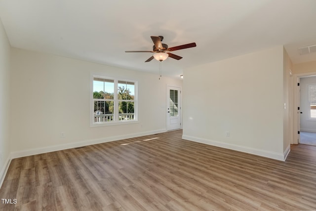 spare room featuring ceiling fan, visible vents, light wood-style flooring, and baseboards