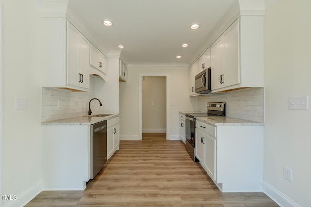 kitchen featuring stainless steel appliances, light wood-type flooring, a sink, and baseboards