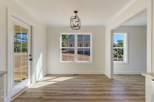 unfurnished dining area with ornamental molding, baseboards, and wood finished floors