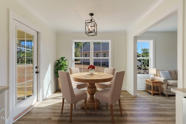 dining room featuring ornamental molding, a notable chandelier, baseboards, and wood finished floors