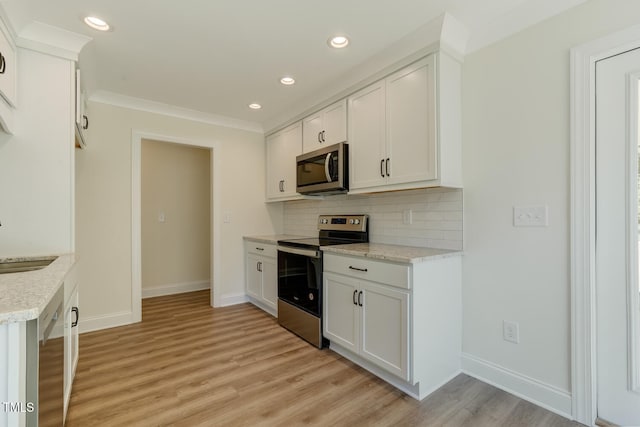 kitchen with appliances with stainless steel finishes, white cabinets, light wood-style floors, and tasteful backsplash