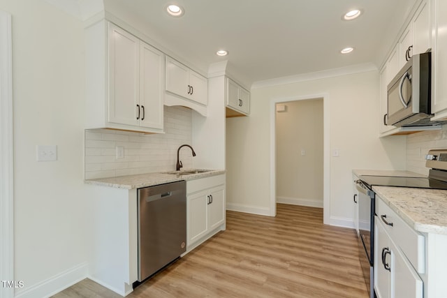 kitchen with baseboards, light wood-style flooring, appliances with stainless steel finishes, white cabinetry, and a sink