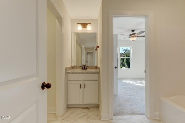 bathroom with baseboards, a tub, ceiling fan, marble finish floor, and vanity