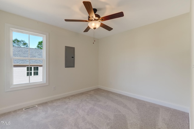 empty room with light colored carpet, electric panel, visible vents, and baseboards