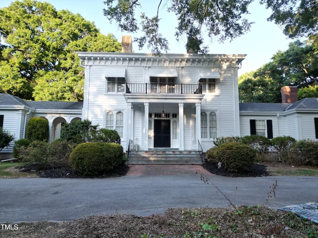 italianate home featuring a chimney and a balcony