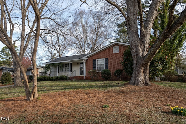 view of front of property featuring covered porch, brick siding, and a front lawn