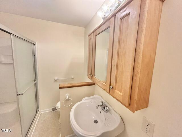 full bath featuring a sink, baseboards, a stall shower, and toilet