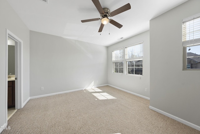 carpeted spare room with ceiling fan, visible vents, and baseboards