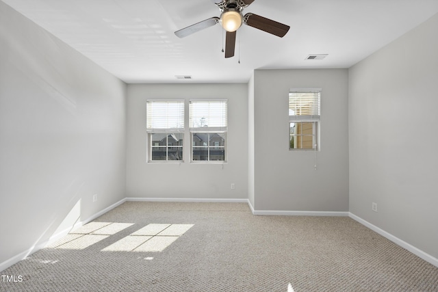 spare room featuring baseboards, visible vents, ceiling fan, and light colored carpet