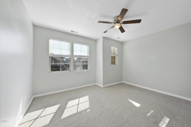 unfurnished room with carpet, baseboards, visible vents, and ceiling fan