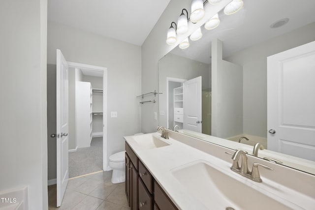 bathroom with double vanity, a spacious closet, a sink, and tile patterned floors