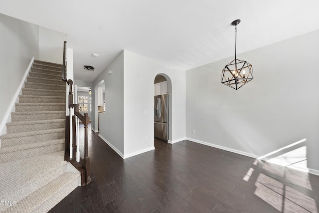 interior space with baseboards, arched walkways, and wood finished floors