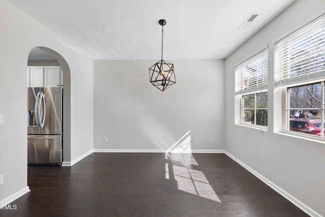 unfurnished dining area featuring dark wood-style flooring, visible vents, and baseboards