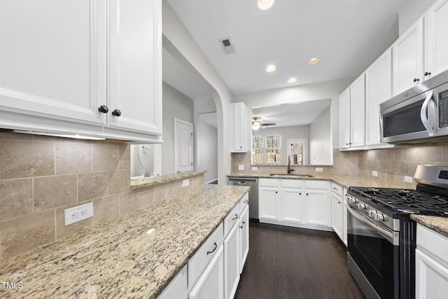 kitchen featuring stainless steel appliances, a sink, visible vents, white cabinets, and dark wood finished floors