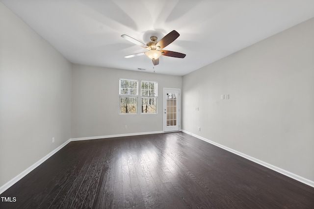 empty room with a ceiling fan, visible vents, baseboards, and dark wood-style flooring