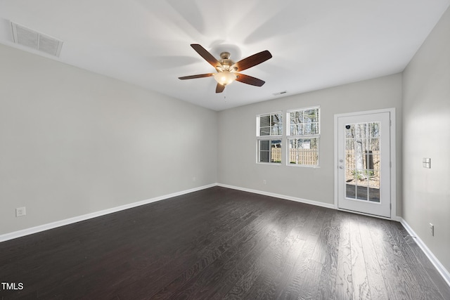 empty room featuring dark wood-style floors, visible vents, baseboards, and a ceiling fan