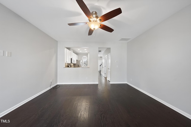 unfurnished living room featuring dark wood-type flooring, visible vents, ceiling fan, and baseboards