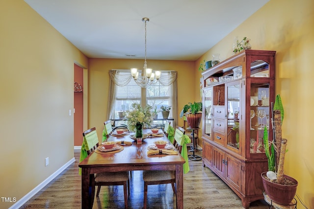 dining room featuring visible vents, light wood-style floors, baseboards, and a chandelier