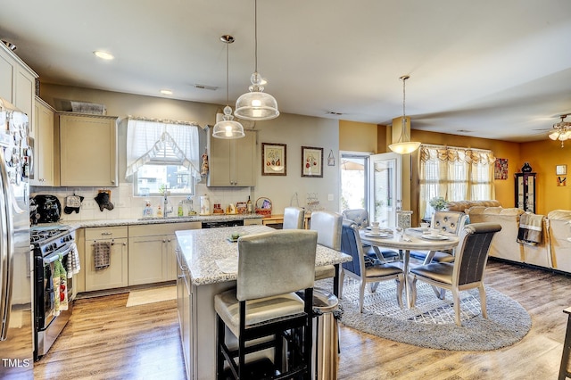 kitchen with visible vents, light wood-style flooring, a sink, stainless steel gas range oven, and open floor plan