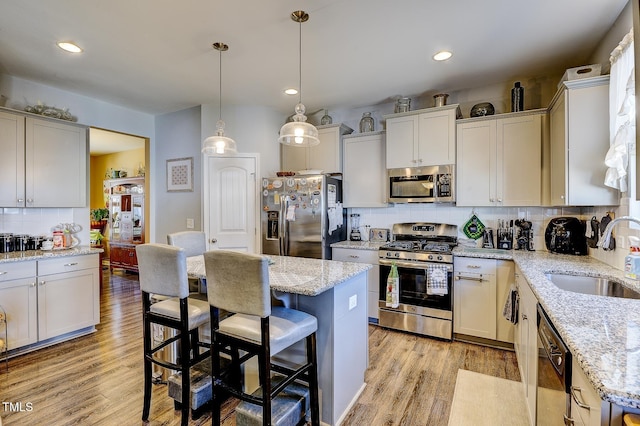 kitchen featuring light wood-style flooring, a kitchen breakfast bar, stainless steel appliances, and a sink