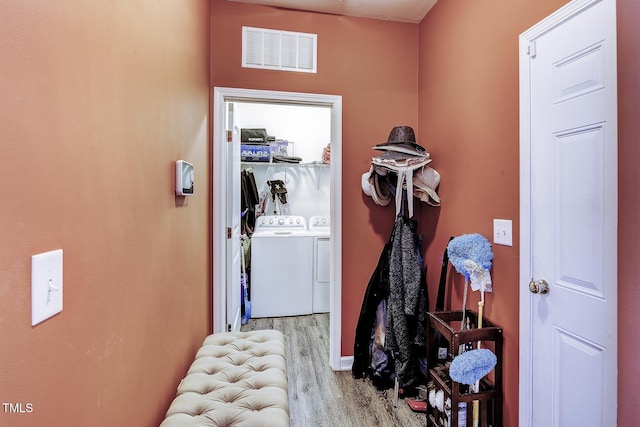 corridor featuring visible vents, wood finished floors, and washing machine and clothes dryer