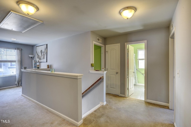 corridor featuring baseboards, visible vents, attic access, an upstairs landing, and light colored carpet