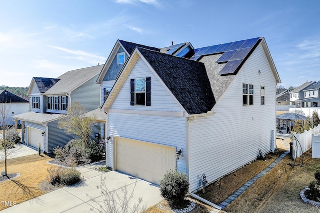 view of home's exterior with solar panels, fence, a garage, and driveway