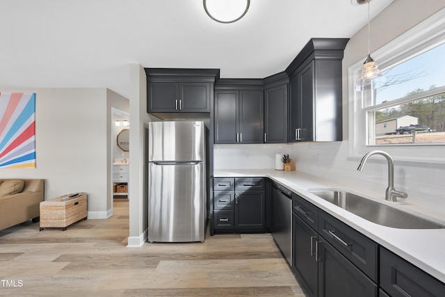 kitchen with light wood-type flooring, backsplash, stainless steel appliances, and a sink