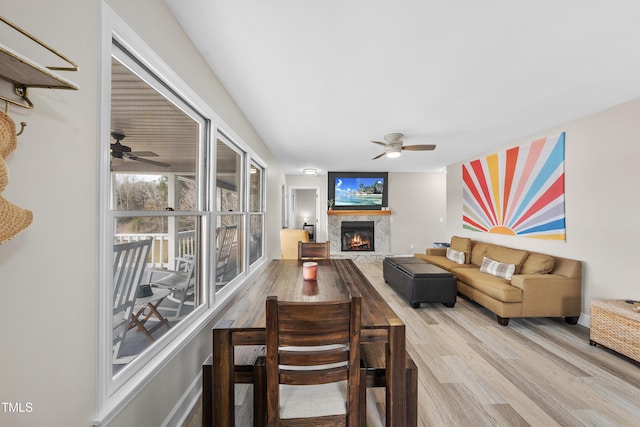 living room with ceiling fan, a glass covered fireplace, and wood finished floors