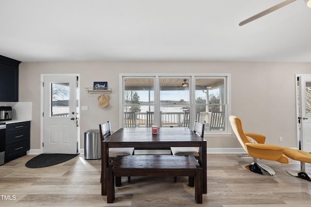 dining room featuring light wood finished floors, a ceiling fan, and baseboards