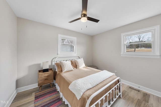 bedroom featuring baseboards, visible vents, and wood finished floors