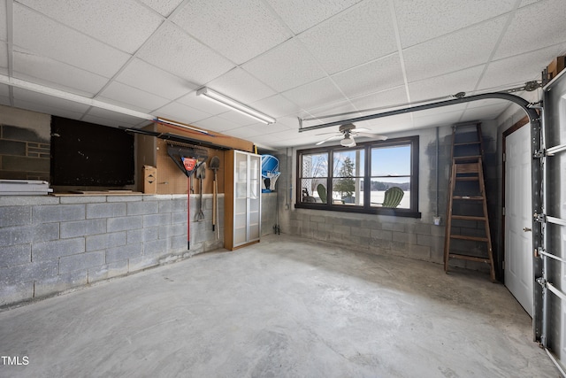 basement with ceiling fan, a drop ceiling, and concrete block wall