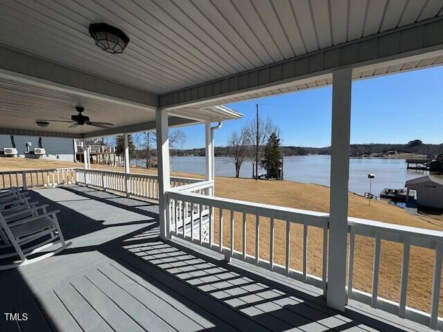 wooden terrace featuring a ceiling fan and a water view