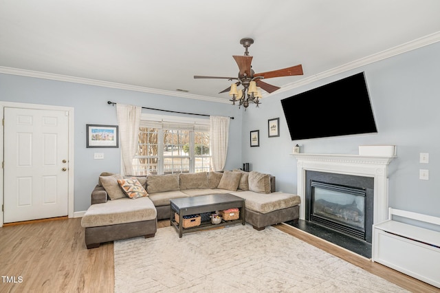 living room featuring visible vents, a ceiling fan, a fireplace with flush hearth, ornamental molding, and wood finished floors