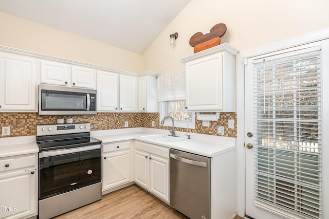 kitchen with vaulted ceiling, appliances with stainless steel finishes, decorative backsplash, and a sink