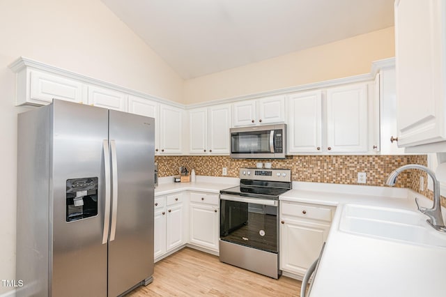 kitchen featuring lofted ceiling, tasteful backsplash, stainless steel appliances, and a sink