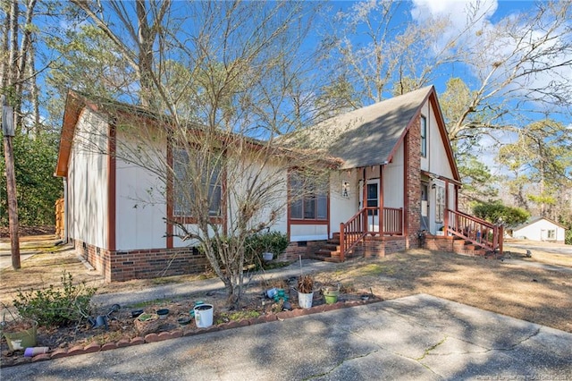 view of front facade with a shingled roof and crawl space