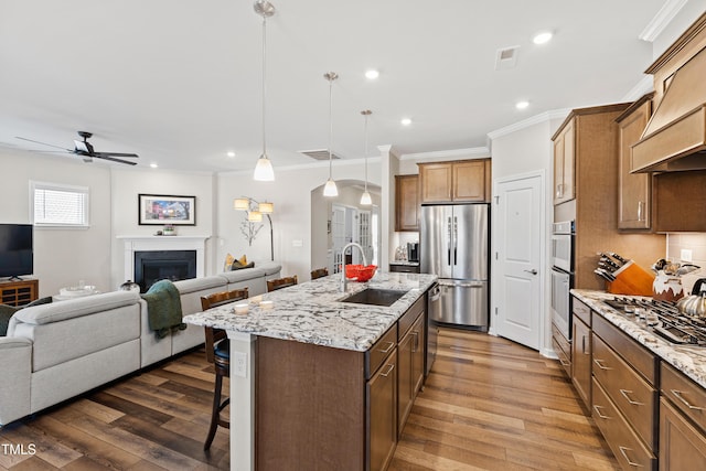 kitchen with a fireplace, appliances with stainless steel finishes, open floor plan, a sink, and a kitchen breakfast bar