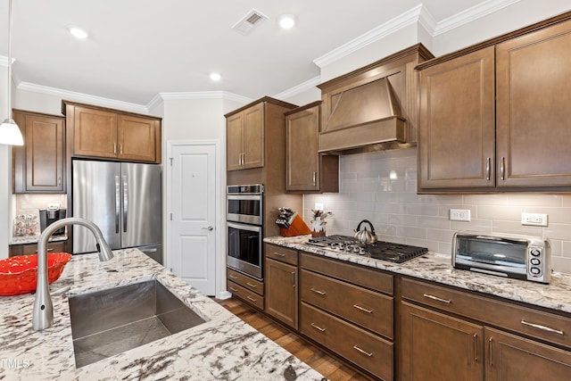 kitchen with a toaster, custom range hood, visible vents, appliances with stainless steel finishes, and a sink