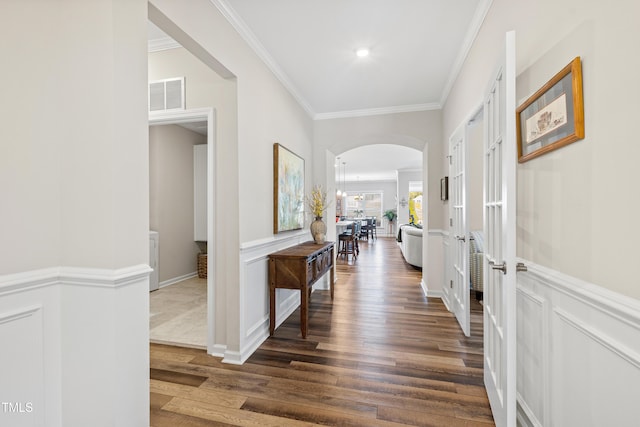 hallway with visible vents, ornamental molding, arched walkways, and dark wood-style flooring