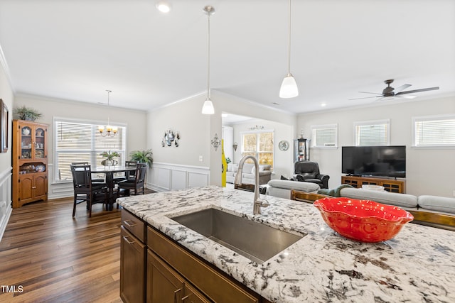 kitchen with open floor plan, wood finished floors, a sink, and decorative light fixtures