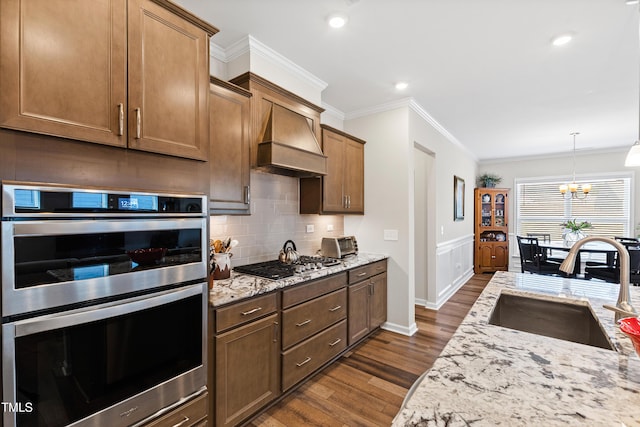 kitchen with dark wood-style floors, custom exhaust hood, stainless steel appliances, crown molding, and a sink