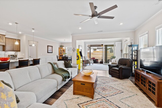 living room with dark wood finished floors, a ceiling fan, wainscoting, ornamental molding, and recessed lighting