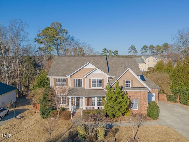 traditional-style home with driveway, a porch, and brick siding