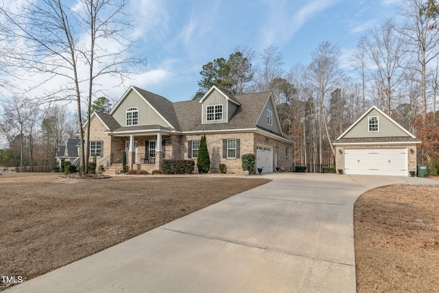 craftsman inspired home with a garage, covered porch, brick siding, and driveway