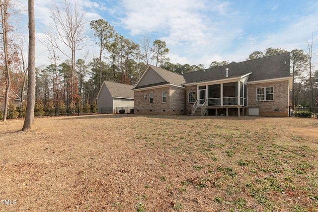 rear view of house featuring brick siding, fence, a sunroom, a lawn, and crawl space