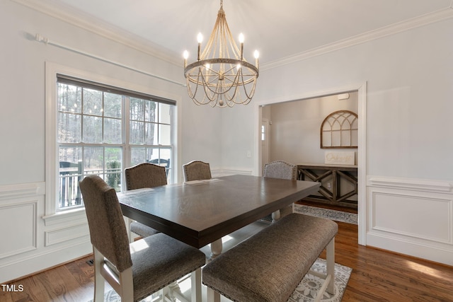 dining area with ornamental molding, a decorative wall, wood finished floors, and a healthy amount of sunlight