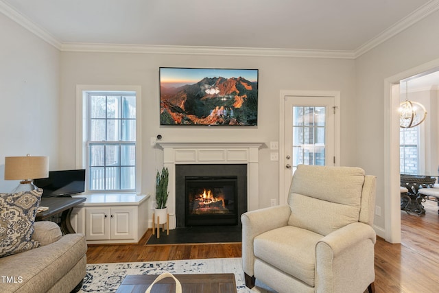 living area featuring dark wood-style floors, a fireplace with flush hearth, crown molding, and an inviting chandelier