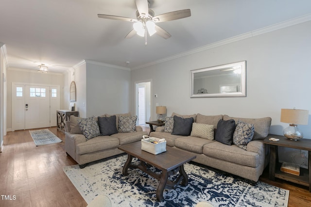 living room featuring light wood finished floors, ornamental molding, and a ceiling fan