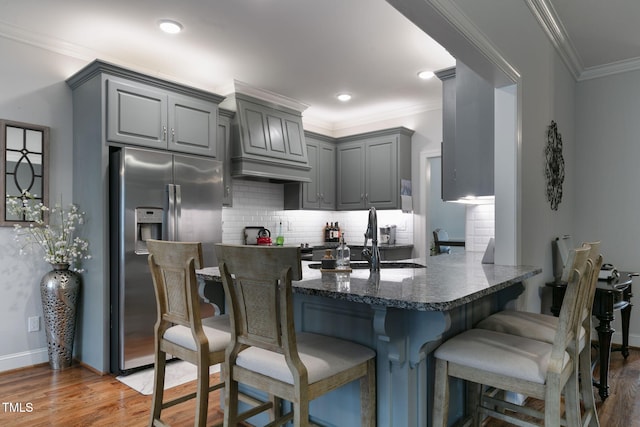 kitchen with light wood-type flooring, stainless steel fridge, backsplash, and gray cabinetry